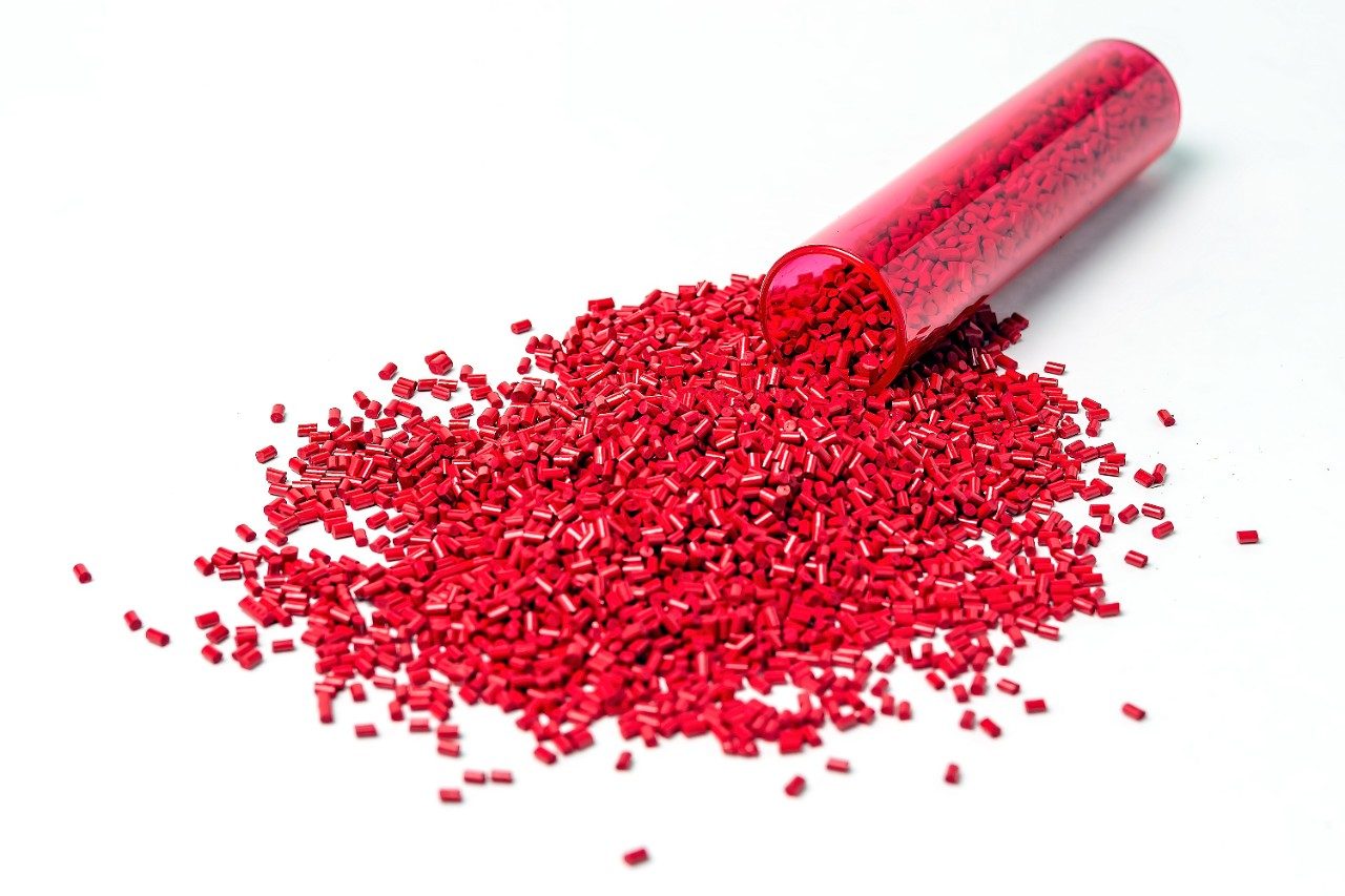 Red polymer plastic granules spilling out of test tube