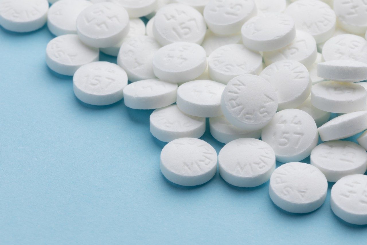 White aspirin pills on blue paper background