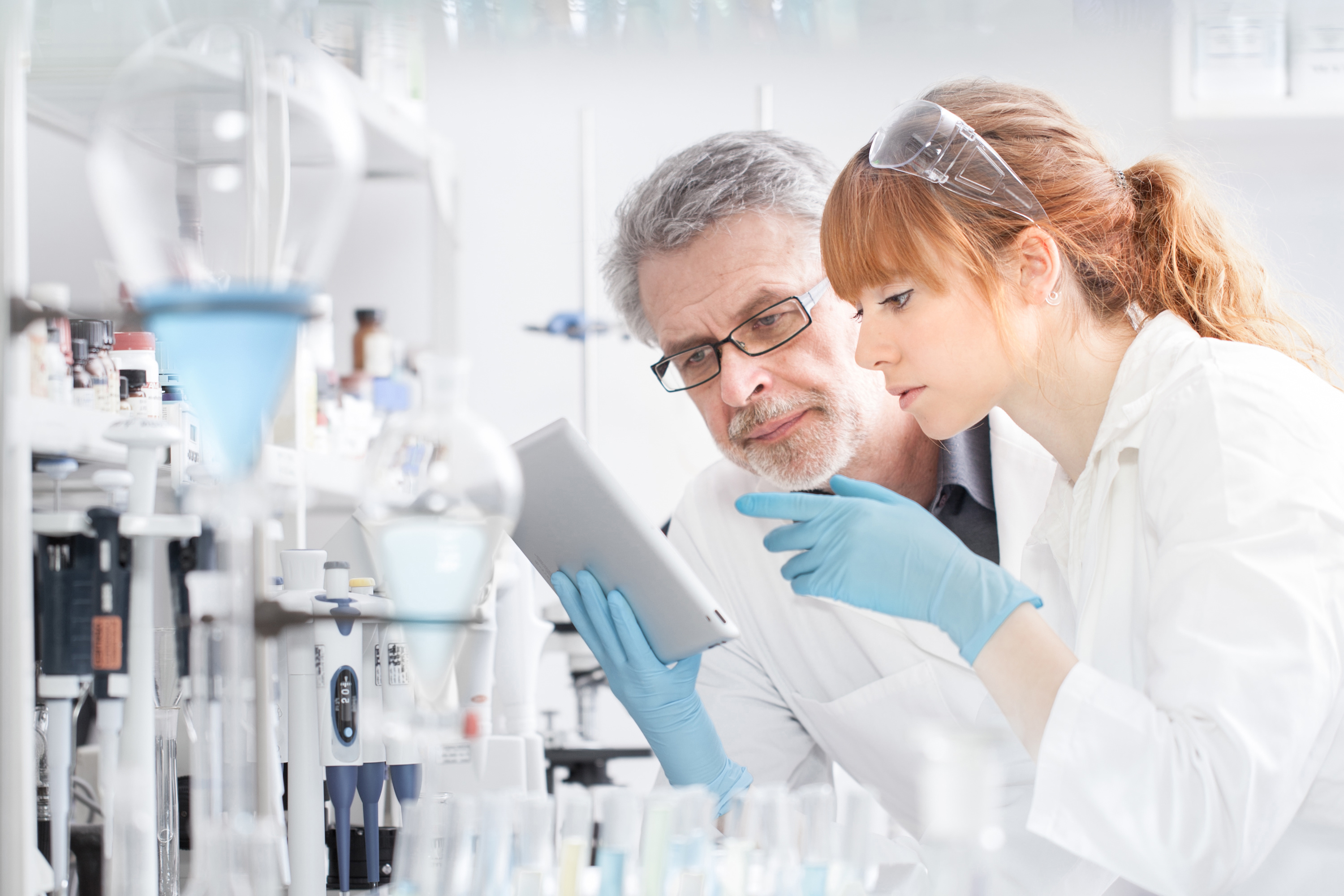 Researchers working in scientific laboratory looking at tablet