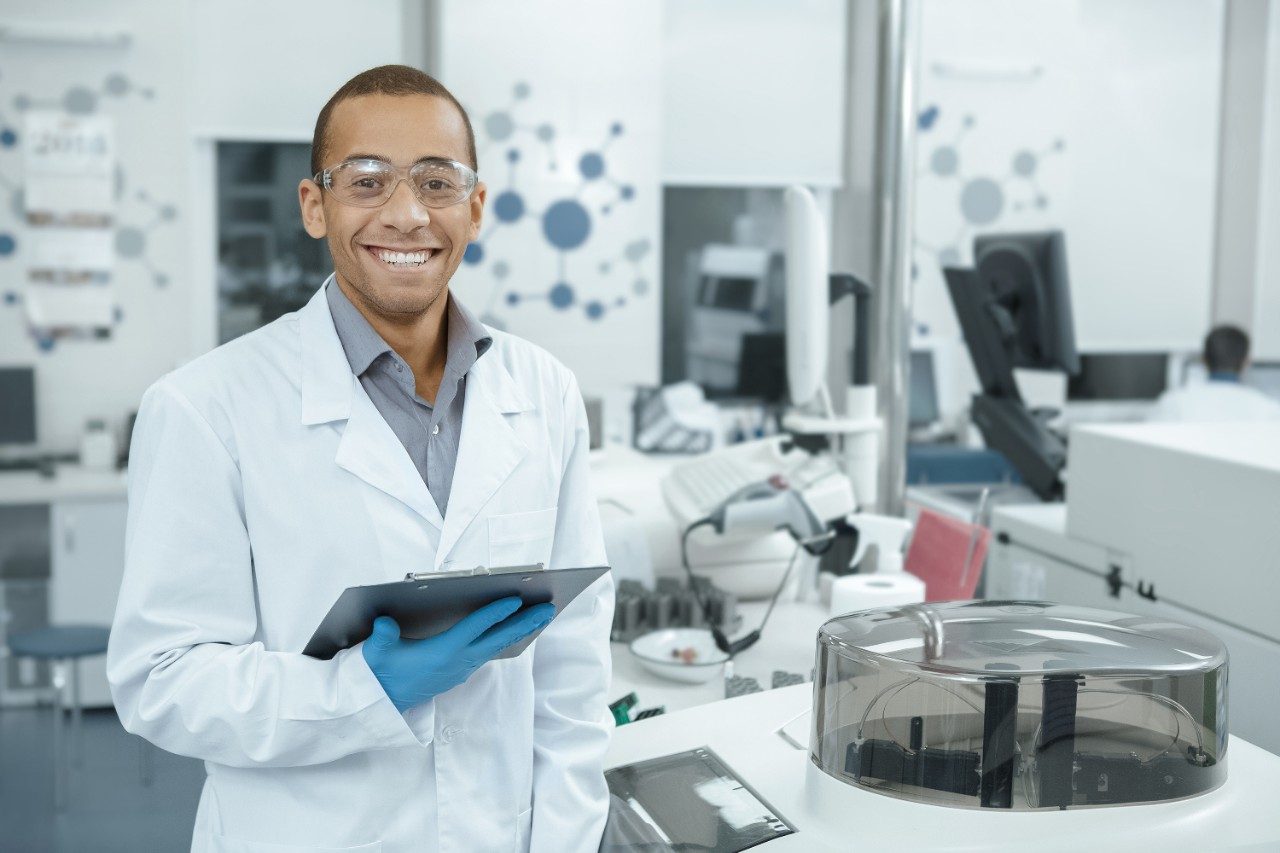 Scientist smiling holding clipboard in lab