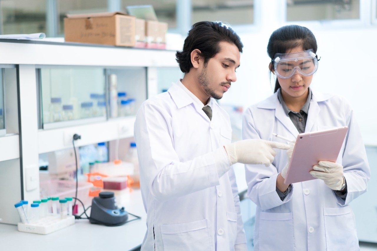 Scientists asian in the laboratory they use a tablet recording the results.