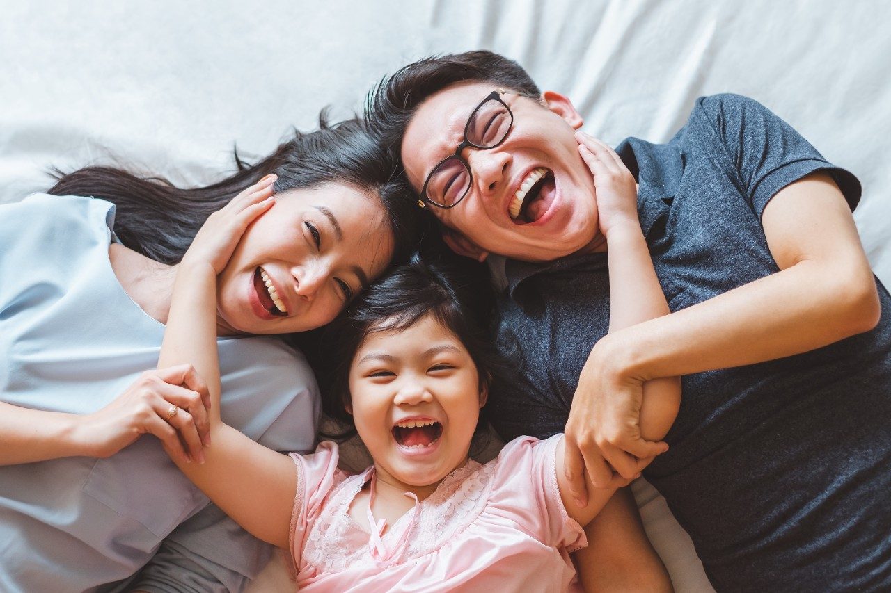 Happy Asian family laying on bed in bedroom